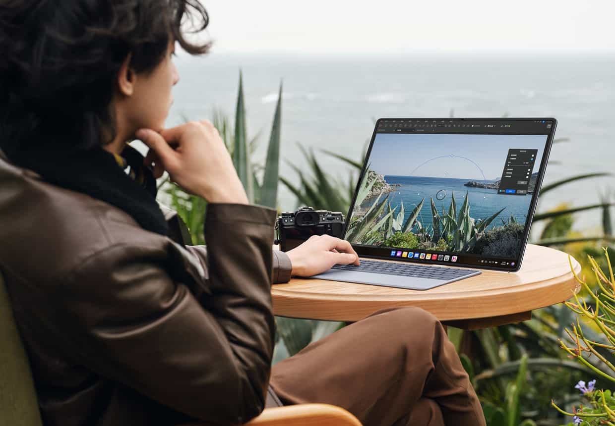 一个男人在户外的桌子旁横屏使用 HUAWEI MateBook Fold 非凡大师浏览拍摄的图片