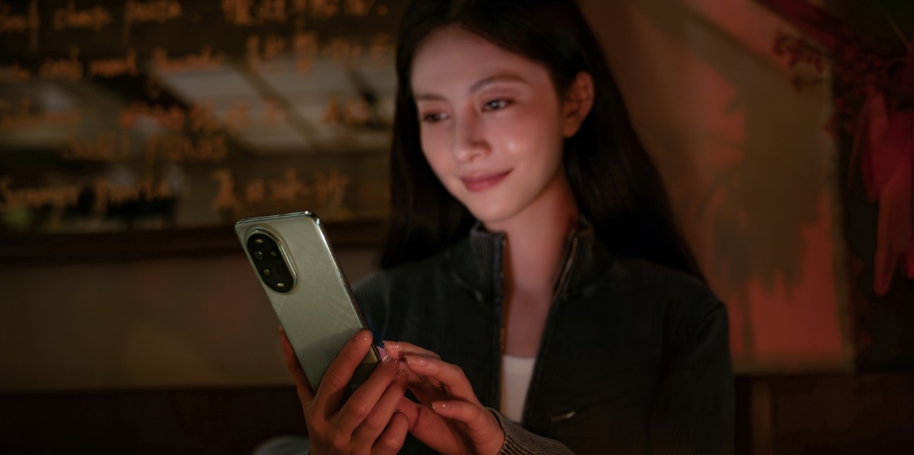 A female model using HUAWEI nova 13 Pro in low-light conditions, demonstrating the AI Eye Comfort Display